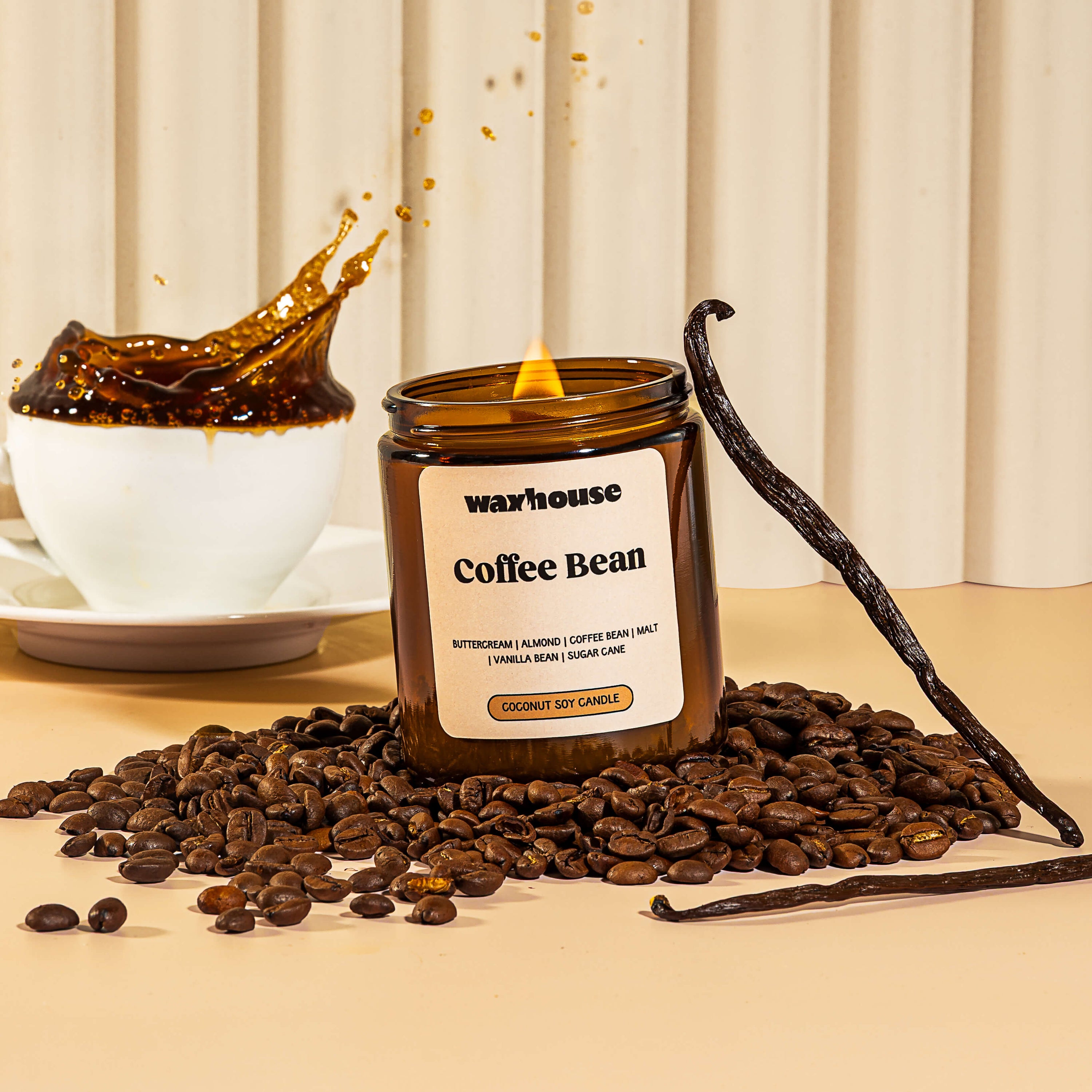 Waxhouse Coffee Bean candle with coffee beans and a vanilla bean on a beige surface.