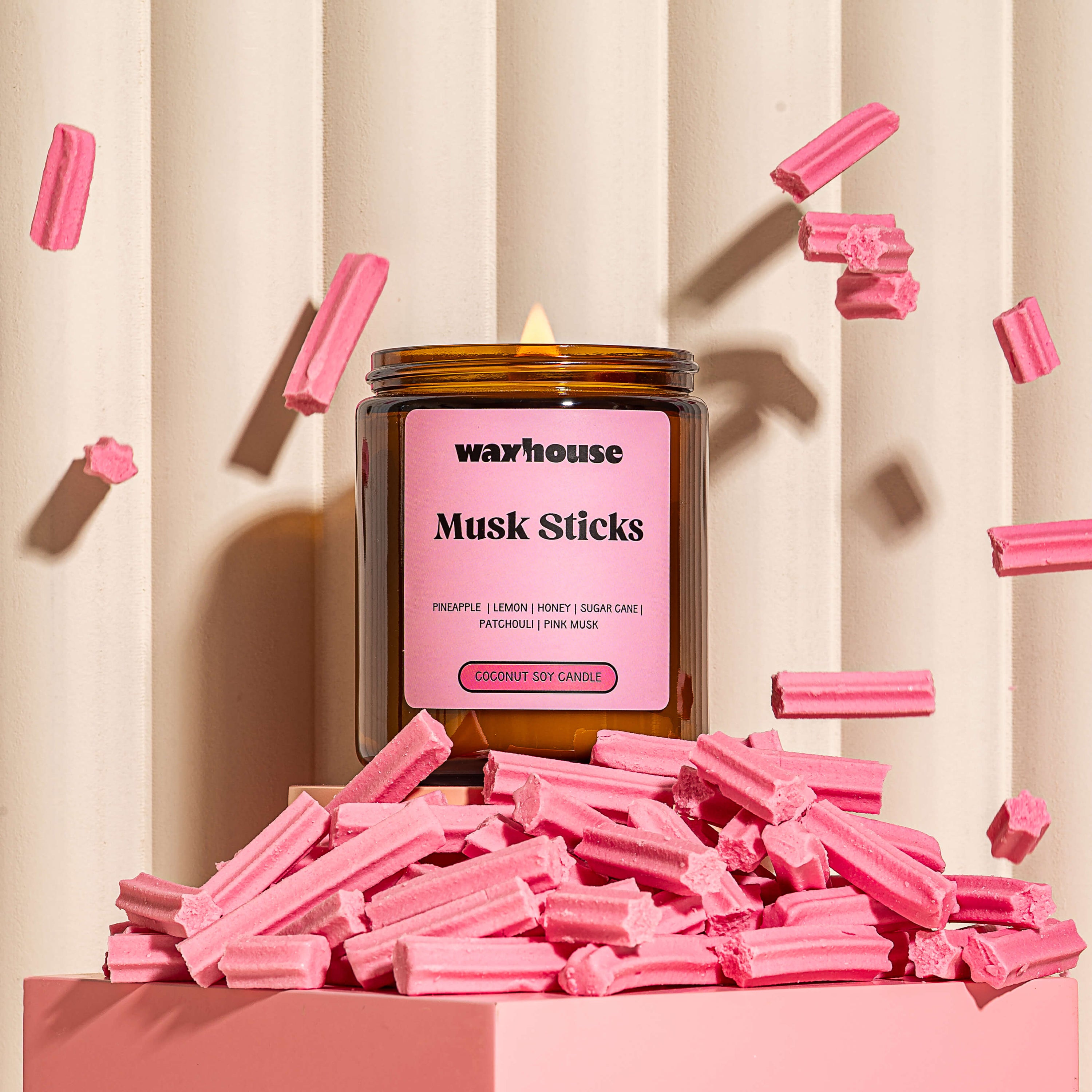 Waxhouse musk sticks candle sitting on a podeum with musk sticks falling